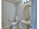 A well-lit powder room with a pedestal sink, oval mirror, and neutral wall color at 1417 Leamington Ln, Winter Haven, FL 33884