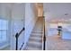 View of the staircase with carpeted steps, wood handrail, and a partial view of the open kitchen at 1417 Leamington Ln, Winter Haven, FL 33884