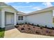 A welcoming view of the home's entrance with tidy landscaping, concrete walkway, and light-colored stucco exterior at 4502 Fairway Oaks Dr, Mulberry, FL 33860