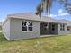 Back exterior of home showing lawn and covered patio with exterior neutral colored paint and windows at 4537 Fairway Oaks Dr, Mulberry, FL 33860