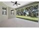 Expansive covered patio with ceiling fan offering serene views of the landscaped yard and lake at 4537 Fairway Oaks Dr, Mulberry, FL 33860