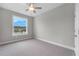 Cozy bedroom features neutral carpet, a ceiling fan and a view of the outdoors from a bright window at 4541 Fairway Oaks Dr, Mulberry, FL 33860