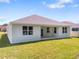 A view of the backyard with a grassy area and a covered patio with glass doors at 4545 Fairway Oaks Dr, Mulberry, FL 33860