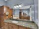 Bathroom vanity featuring granite countertops, wooden cabinets, and a large mirror at 6487 Ashley Dr, Lakeland, FL 33813