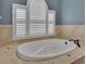 Luxurious soaking tub with elegant fixtures, tile surround, and shuttered windows at 6487 Ashley Dr, Lakeland, FL 33813