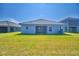 Spacious backyard with a well-maintained lawn and a modern house featuring a covered patio at 4670 Grandview Glen Dr, Auburndale, FL 33823