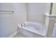 Bathtub in neutral-toned bathroom with light tile floors and updated fixtures at 4938 Vue Delac Pass, Auburndale, FL 33823