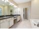 Bathroom featuring double vanities, a large mirror, a soaking tub, and a walk-in closet at 8288 Lake James Dr, Lakeland, FL 33810