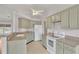 A well-lit kitchen features light green cabinets, white appliances, and tile flooring at 5879 Swallow Dr, Lakeland, FL 33809