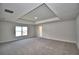 Spacious main bedroom featuring tray ceilings, neutral paint, carpeted floors, and natural light at 5280 Tennessee Ridge Ct, Auburndale, FL 33823