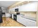 Galley kitchen featuring white cabinets, granite countertops, black appliances, and tile flooring at 1144 Waterfall Ln # 26, Lakeland, FL 33803