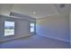 Spacious bedroom featuring neutral carpeting, tray ceiling, and natural light from two windows at 5120 Villa Crest Way, Auburndale, FL 33823
