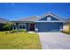 Charming single-story home with a blue exterior, well-manicured lawn, and a gray tiled roof under a clear blue sky at 5120 Villa Crest Way, Auburndale, FL 33823