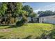 Backyard with lush landscaping, partial fence, and partial view of house with lots of sunlight and green grass at 2470 Avenue E Sw, Winter Haven, FL 33880