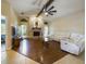 Open-concept living room with brick fireplace, wood floors, a large ceiling fan, and white sofa at 1323 Hammock Shade Dr, Lakeland, FL 33809