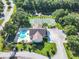 Aerial view of a community pool, clubhouse, and tennis courts next to a pond at 665 Lake Clark Pl, Lakeland, FL 33813