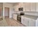 Modern kitchen showcasing white cabinets, stainless steel appliances, and granite countertops with wood-look tile flooring at 4538 Grandview Glen Dr, Auburndale, FL 33823