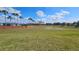 A large grassy open space features a perimeter lined with palm trees and brick privacy wall against a partly cloudy sky at 4544 Grand View Glen Dr, Auburndale, FL 33823
