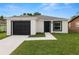 Single-story home featuring a black garage door and front door surrounded by a manicured lawn at 1918 Dr Martin L King Jr Way, Haines City, FL 33844