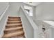Carpeted staircase with white banister, natural light from upstairs window at 6857 Eagle Ridge Loop, Lakeland, FL 33813