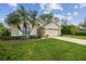 Beautiful exterior view of home with lush green lawn, mature trees, and a beige two-car garage at 1045 View Pointe Way, Lakeland, FL 33813