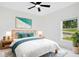 Bright bedroom features white walls, ceiling fan, modern decor, and a large window overlooking the yard at 1896 12Th St, Orange City, FL 32763