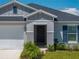 Inviting front entrance with a black front door, a two car garage, and manicured landscaping at 1029 Mattie Pointe Way, Auburndale, FL 33823