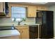 Well-lit kitchen with wooden cabinets, black appliances, double sinks, and a window with potted plants at 480 Nighthawk Dr, Lakeland, FL 33813