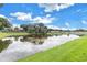 Scenic pond with blue sky reflection, bordered by lush green grass, creating a peaceful backyard oasis at 6414 Highlands In The Woods St, Lakeland, FL 33813