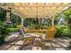 Peaceful patio featuring a pergola, yellow metal table and chairs, lush landscaping at 7525 Catherine Dr, Lakeland, FL 33810