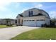 Tan two-story house with a two-car garage and lush green lawn at 206 Clovis Pass, Winter Haven, FL 33880