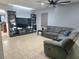 Comfortable living room features tile floors, ceiling fan, TV, and a grey sectional sofa at 1109 Brenton Manor Dr, Winter Haven, FL 33881