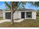 Charming single-story home featuring a black garage door and door, complemented by a well-manicured front yard and landscaping at 1217 Avenue J, Haines City, FL 33844