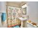 Bathroom with pedestal sink, shower/tub combo, and beach-themed decor at 415 W Beacon Rd, Lakeland, FL 33803