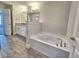Bright bathroom featuring soaking tub, granite countertop, and wood look flooring at 4682 Grandview Glen Dr, Auburndale, FL 33823