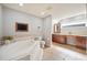 Bathroom featuring jacuzzi tub, television, double sink vanity, and bronze fixtures and tile flooring at 5009 Hanover Ln, Lakeland, FL 33813