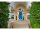 Charming home featuring a lovely archway entryway, bright blue door, and manicured landscaping at 5009 Hanover Ln, Lakeland, FL 33813