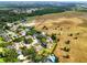 Expansive aerial view of a residential area, showcasing a neighborhood bordering a large open field and wooded area at 1935 Austin Ter, Winter Haven, FL 33884