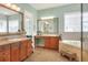 Bright bathroom with double sinks, a makeup vanity, large mirrors, and a soaking tub with a stool at 1935 Austin Ter, Winter Haven, FL 33884