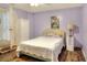 Bedroom with hardwood floors, lilac painted walls, a cozy bed, and closet with bi-fold doors at 1935 Austin Ter, Winter Haven, FL 33884