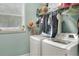 Bright laundry room featuring a washer, a dryer, and storage shelves for supplies at 1935 Austin Ter, Winter Haven, FL 33884