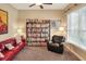 Cozy living room with a full bookcase, a comfortable couch, natural light from a window, and a ceiling fan at 1935 Austin Ter, Winter Haven, FL 33884