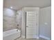 Bathroom with tile surround, tub, and white door at 4688 Grandview Glen Dr, Auburndale, FL 33823
