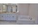 Bathroom featuring dual sink vanity with granite counters and a soaking tub at 4688 Grandview Glen Dr, Auburndale, FL 33823