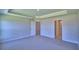 Large bedroom with a tray ceiling, carpeted floor, and multiple doors at 4700 Grandview Glen Dr, Auburndale, FL 33823