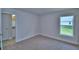 Neutral bedroom includes a window with backyard views, neutral carpet and paint, and white base trim at 4700 Grandview Glen Dr, Auburndale, FL 33823