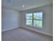 Sun-filled bedroom featuring neutral carpet, large window with neighborhood views, and base trim at 4700 Grandview Glen Dr, Auburndale, FL 33823
