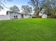 Expansive backyard with lush green lawn, white fence, storage shed, and sliding glass doors to the home at 5225 Golden Gate Blvd, Polk City, FL 33868