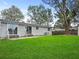 A spacious backyard with well-kept lawn, a concrete patio, and a home with two sliding glass doors at 5225 Golden Gate Blvd, Polk City, FL 33868