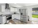 Modern kitchen featuring stainless steel appliances, white cabinets, granite countertops, and wood-look floors at 5225 Golden Gate Blvd, Polk City, FL 33868